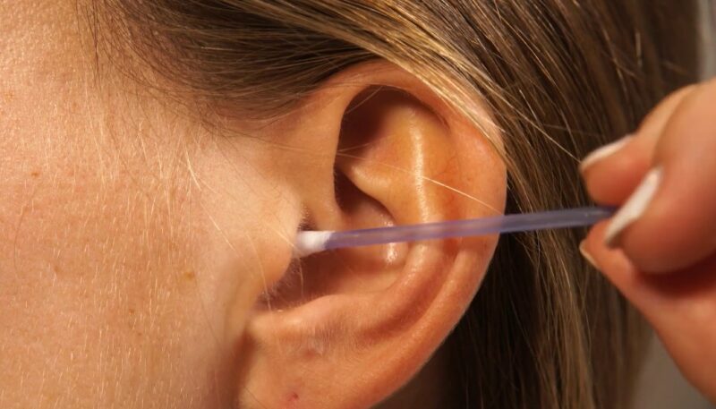 Close up photo of a girl using cotton swab on her ear